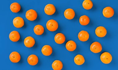 Mavi arka plan üzerinde taze portakal mandalina veya mandalina meyve deseni. Düz yatıyordu, üstten bak. Pop art tasarımı, yaratıcı yaz konsepti. Minimal tarzda narenciye.