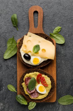 Açık yüzlü sosis sandviç kanepe veya crostini taş koyu arka plan üzerinde bir ahşap hizmet gemide. Üstten görünüm.