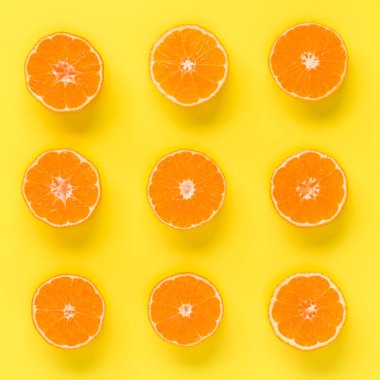 Taze mandalina dilimleri sarı zemin üzerine meyve deseni. Düz yatıyordu, en iyi görünüm. Pop sanat tasarım, yaratıcı yaz konsepti. Minimal tarzda narenciye yarısı. Mandalina.