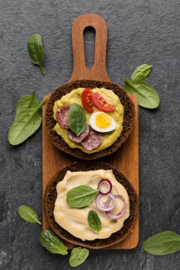 Açık yüzlü sosis sandviç kanepe veya crostini taş koyu arka plan üzerinde bir ahşap hizmet gemide. Üstten görünüm.