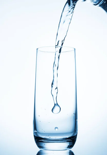 青い背景にガラスに水が流れ込み — ストック写真