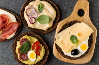 Açık yüzlü sandviç kanepe veya crostini taş koyu arka plan üzerinde bir ahşap hizmet gemide. Üstten görünüm.