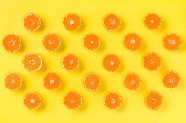 Taze mandalina dilimleri sarı zemin üzerine meyve deseni. Düz yatıyordu, en iyi görünüm. Pop sanat tasarım, yaratıcı yaz konsepti. Minimal tarzda narenciye yarısı. Mandalina.