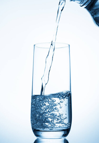 water pouring into glass on blue background