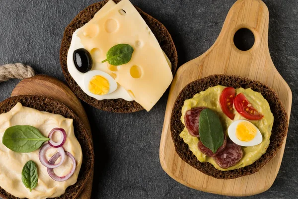 Açık yüzlü sandviç kanepe veya crostini taş koyu arka plan üzerinde bir ahşap hizmet gemide. Üstten görünüm.