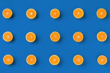 Mavi arka plan üzerinde taze portakal mandalina veya mandalina meyve deseni. Düz yatıyordu, üstten bak. Pop art tasarımı, yaratıcı yaz konsepti. Minimal tarzda narenciye.