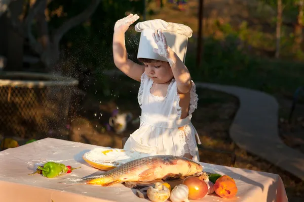 Malý kuchař připravuje ryby — Stock fotografie