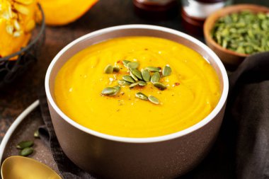 Koyu arkaplanlı kabak kremalı çorba. Geleneksel sonbahar vejetaryen yemeği.