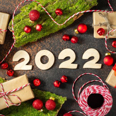 Kırmızı ve beyaz kurdeleli Noel ya da yeni yıl arkaplanı ve çevre dostu el sanatları paketlerinde hediye kutuları. Ahşap numaraları 2022 olan şenlikli bir arka plan. Üst görünüm
