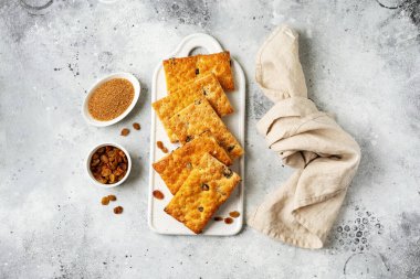 Açık gri mutfak arka planında beyaz tabakta kuru üzümlü tatlı. Lezzetli ev yapımı tatlı poğaça üstü manzaralı