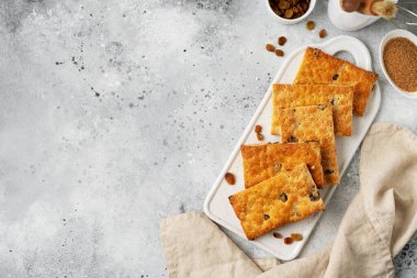 Açık gri mutfak arka planında beyaz tabakta kuru üzümlü tatlı. Lezzetli ev yapımı tatlı poğaça üstü manzaralı