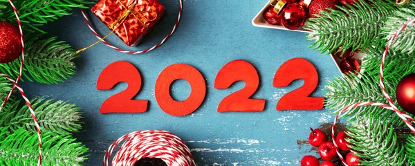 新年快乐 挂满红色圣诞装饰品和冷杉枝条的横幅 节日蓝色背景 木制编号2022 顶部视图 — 图库照片
