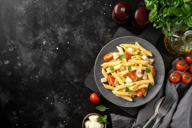 Jambonlu makarna salatası, mozzarella, mısır, domates ve zeytinyağı koyu renk mutfak arka planında seramik tabakta. Geleneksel İtalyan yemeği peynirli ve sebzeli makarna. opyspace