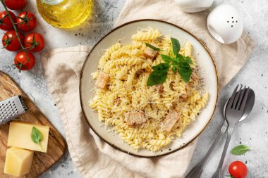 Krema soslu makarna seramik tabakta ve hafif mutfak arka planında. Geleneksel İtalyan yemeği zührevi mutfak masasının üstündeki kasede.