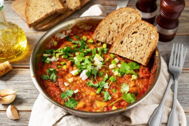 Fasulye, sebze ve kişniş ile ev yapımı vejetaryen güveç. Gri ahşap mutfak arka planında kızartma tavasında yakın plan.