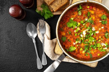 Fasulye, sebze ve kişniş soslu ev yapımı vejetaryen güveç. Arka planda siyah bir tavada.