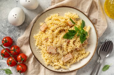 Krema soslu makarna seramik tabakta ve hafif mutfak arka planında. Geleneksel İtalyan yemeği zührevi mutfak masasının üstündeki kasede.