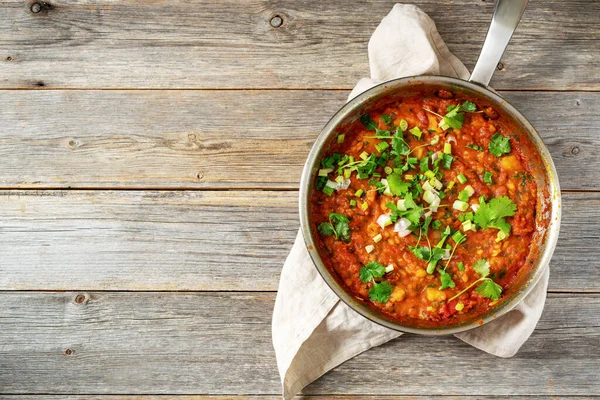Fasulye, sebze ve kişniş ile ev yapımı vejetaryen güveç. Gri ahşap mutfak arka planında kızartma tavasında. Üst görünüm