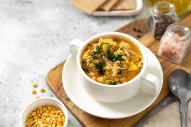 Bezelye çorbası, tavuklu, beyaz tabakta, hafif bir yemek masasında.