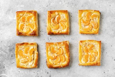 Peynir kremalı mini puf böreği, badem ve mutfak masasında mandalina. Turunçgil meyveli, turunçgil ya da ricotta soslu, fındıklı, arka planda mutfak manzaralı lezzetli bir kare.