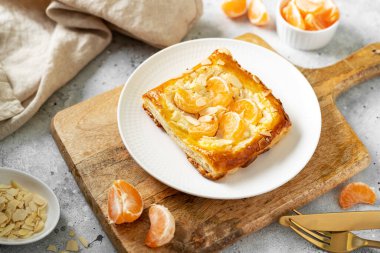 Mutfak masasındaki tabakta peynirli krema, badem ve mandalinalı mini puf böreği. Limon meyveli, dorblue ya da ricotta soslu, fındık aromalı, lezzetli bir kare.
