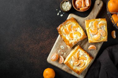 Mutfak masasındaki tabakta peynirli krema, badem ve mandalinalı mini puf böreği. Turunçgil meyveli, turunçgil ya da ricotta soslu, fındıklı, arka planda mutfak manzaralı lezzetli bir kare.