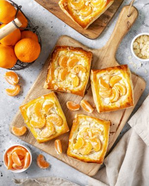 Mutfak masasındaki tabakta peynirli krema, badem ve mandalinalı mini puf böreği. Limon meyveli, dorblue ya da ricotta soslu, fındık aromalı, lezzetli bir kare.