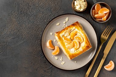 Mutfak masasındaki tabakta peynirli krema, badem ve mandalinalı mini puf böreği. Turunçgil meyveli, turunçgil ya da ricotta soslu, fındıklı, arka planda mutfak manzaralı lezzetli bir kare.
