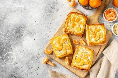 Mutfak masasındaki tabakta peynirli krema, badem ve mandalinalı mini puf böreği. Limon meyveli, dorblue ya da ricotta soslu, fındık aromalı, lezzetli bir kare.