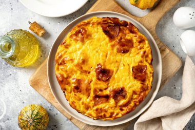 Hafif bir mutfak arka planında seramik tabakta balkabağı, domuz pastırması ve ricotta ile bir parça frittata. Geleneksel İtalyan lezzetli ev yapımı yumurta tabağı mutfak masasının üstünde.