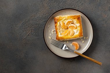 Mutfak masasındaki tabakta peynirli krema, badem ve mandalinalı mini puf böreği. Turunçgil meyveli, turunçgil ya da ricotta soslu, fındıklı, arka planda mutfak manzaralı lezzetli bir kare.