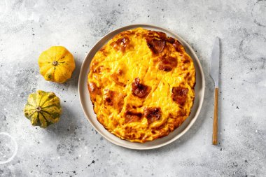 Hafif bir mutfak arka planında seramik tabakta balkabağı, domuz pastırması ve ricotta ile bir parça frittata. Geleneksel İtalyan lezzetli ev yapımı yumurta tabağı mutfak masasının üstünde.