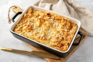 Açık gri mutfak arka planında bir kabın içinde puding ya da yulaf ezmesi turtası. Mutfak masasında fındıklı mısır gevreği, yakın plan. Sağlıklı ve besleyici bir kahvaltı.