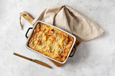 Açık gri mutfak arka planında bir kabın içinde puding ya da yulaf ezmesi turtası. Mutfak masasının üstünde fındıklı mısır gevreği. Sağlıklı ve besleyici bir kahvaltı.