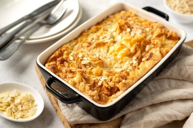 Açık gri mutfak arka planında bir kabın içinde puding ya da yulaf ezmesi turtası. Mutfak masasında fındıklı mısır gevreği, yakın plan. Sağlıklı ve besleyici bir kahvaltı.