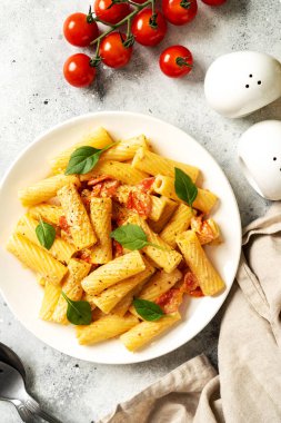 Domatesli tortiglioni, ricotta ve fesleğen, açık mutfak masasında beyaz bir tabakta. Geleneksel İtalyan makarnası, sebzeli ve kremalı süzme peynirli. Üst görünüm