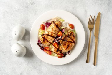 Açık gri mutfak arka planında, beyaz tabakta sebzeli ızgara tavuk filetosu. Mutfak masasında beslenme kümes hayvanları göğsü