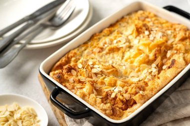 Açık gri mutfak arka planında bir kabın içinde puding ya da yulaf ezmesi turtası. Mutfak masasında fındıklı mısır gevreği, yakın plan. Sağlıklı ve besleyici bir kahvaltı.