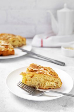 Hafif bir mutfak arka planında beyaz bir tabakta bir parça elmalı turta. Charlotte 'la turta yakın planda olacak. Mutfak masasında nefis ev yapımı hamur işi.