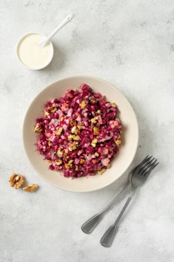 Salatalık turşulu pancar salatası, ceviz, elma ve mayonez açık gri mutfak masasında. Üst görünüm