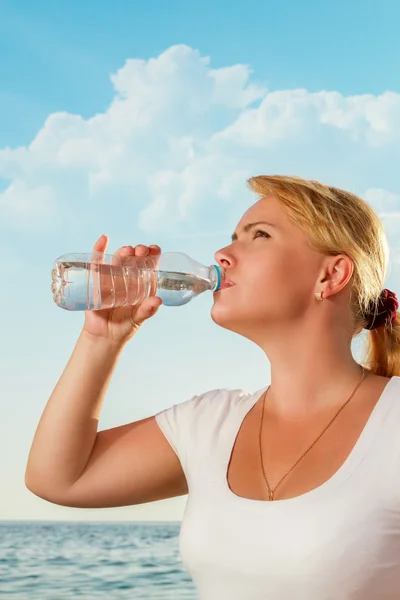 Krásná žena pít sladké vody z láhve na tropické bea — Stock fotografie