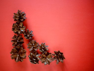 Kırmızı arka planda çam kozalakları olan bir Noel arkaplanı.