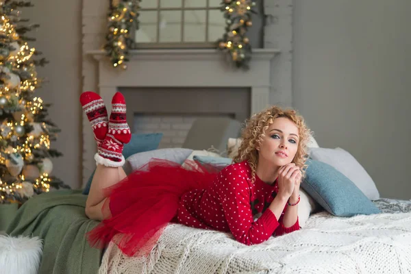 Kıvırcık saçlı, kırmızı örgü elbiseli, Noel ağacı olan neşeli bir kadın.