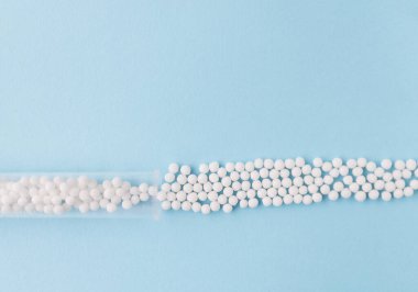 Mavi arka planda homeopatik haplar ve plastik kap. Homeopatik ilaç.