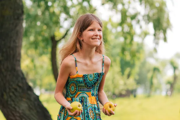 髪の長い可愛い若い女の子が手にりんごを見ている 夏の日 子供は庭で果物を集める 子供のための新鮮な健康食品 夏の家庭料理 — ストック写真