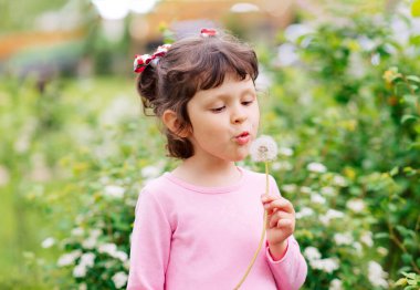 Bahar günü açık havada, leylak çiçekleriyle gezen küçük tatlı bir kızın portresi. Aromaterapi.