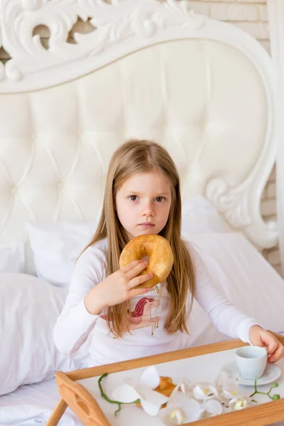 Κορίτσι Τρώει Πρωινό Στο Κρεβάτι Κύπελλο Και Ντόνατ Φωτεινό Εσωτερικό — Φωτογραφία Αρχείου