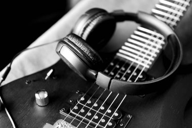 Siyah elektro gitarda siyah kulaklıklar. Müzikal yaşam tarzı.