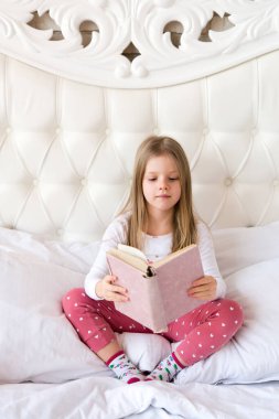 küçük kız yatakta kitap okuma