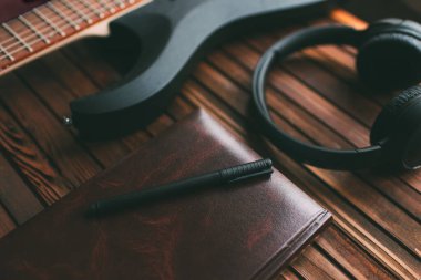 Kulaklıklar, defter ve gitar tahta bir masada. Müzik teması.